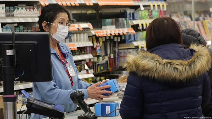 一名亚裔店员站在收银台前 一名亚裔店员站在收银台前