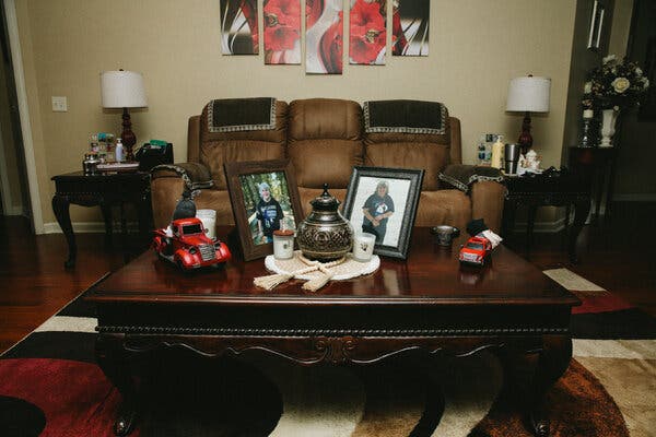 An urn sits at the center of a table, with candles and photos of a woman on either side.